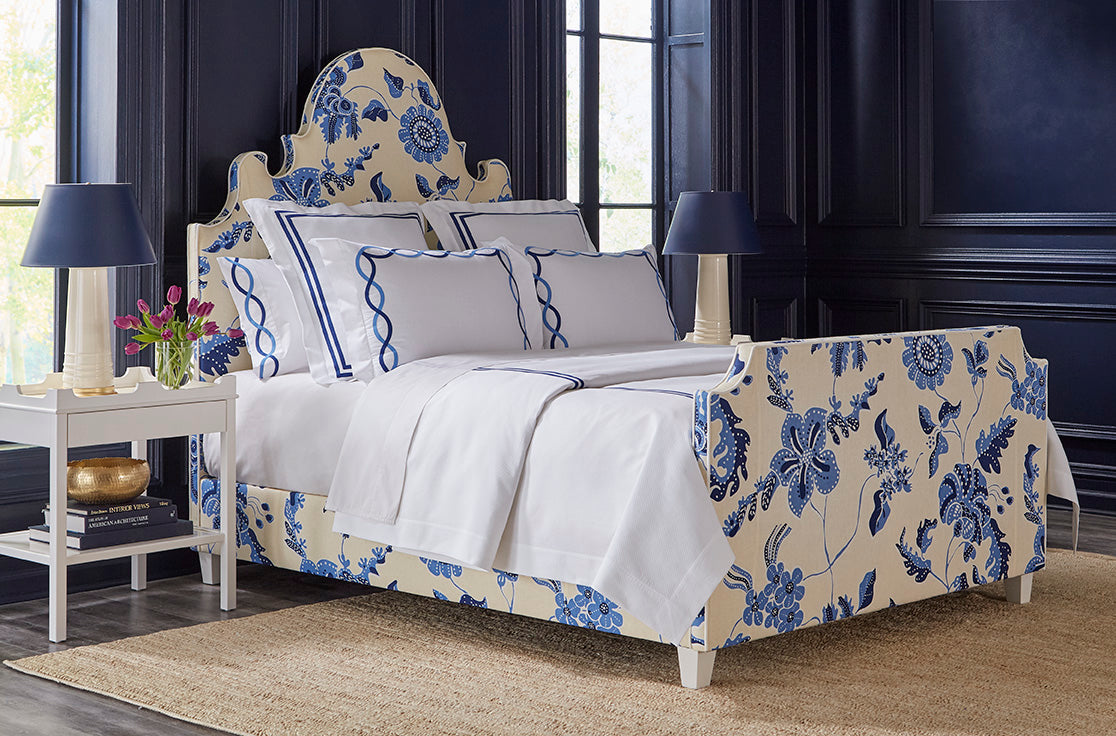 Dark blue bedroom featuring a bedframe with a blue flower pattern and a sleek white night stand.